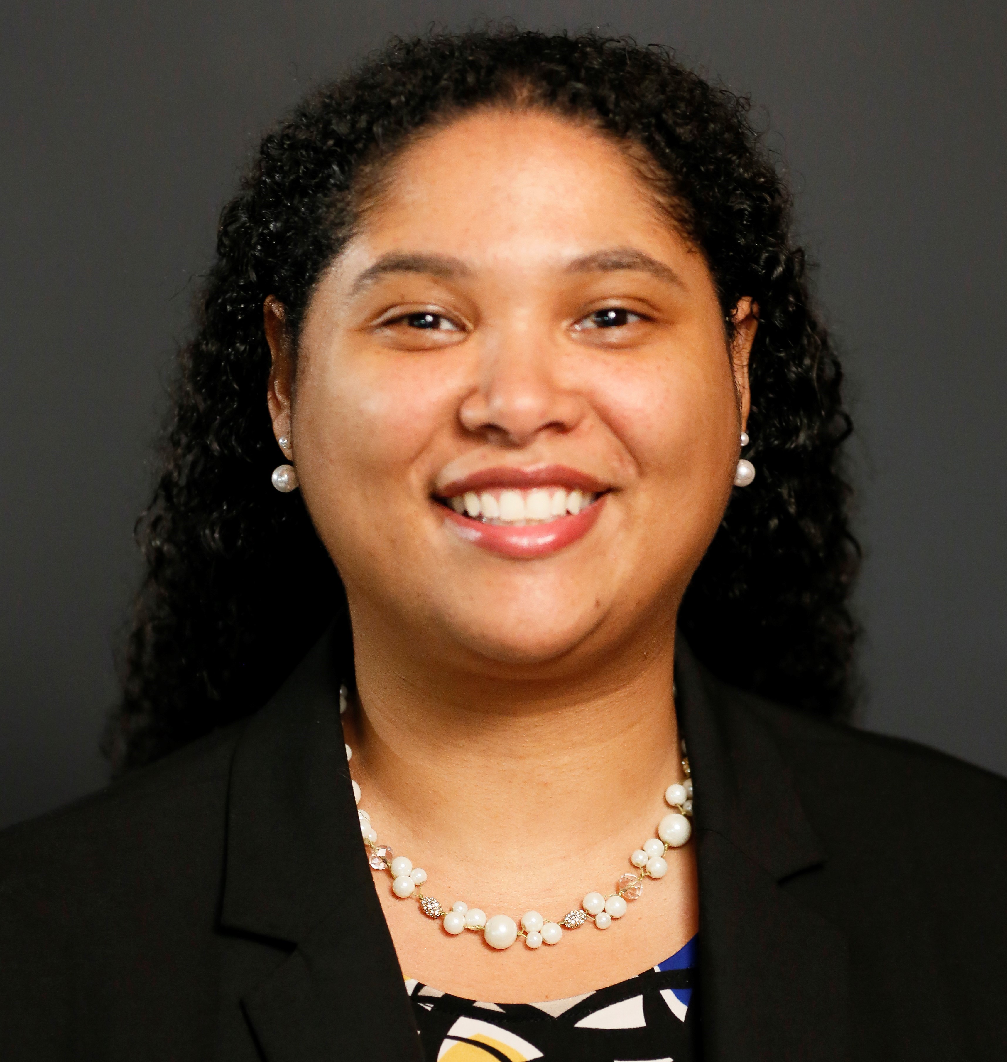 Woman with curly, dark hair smiling at camera