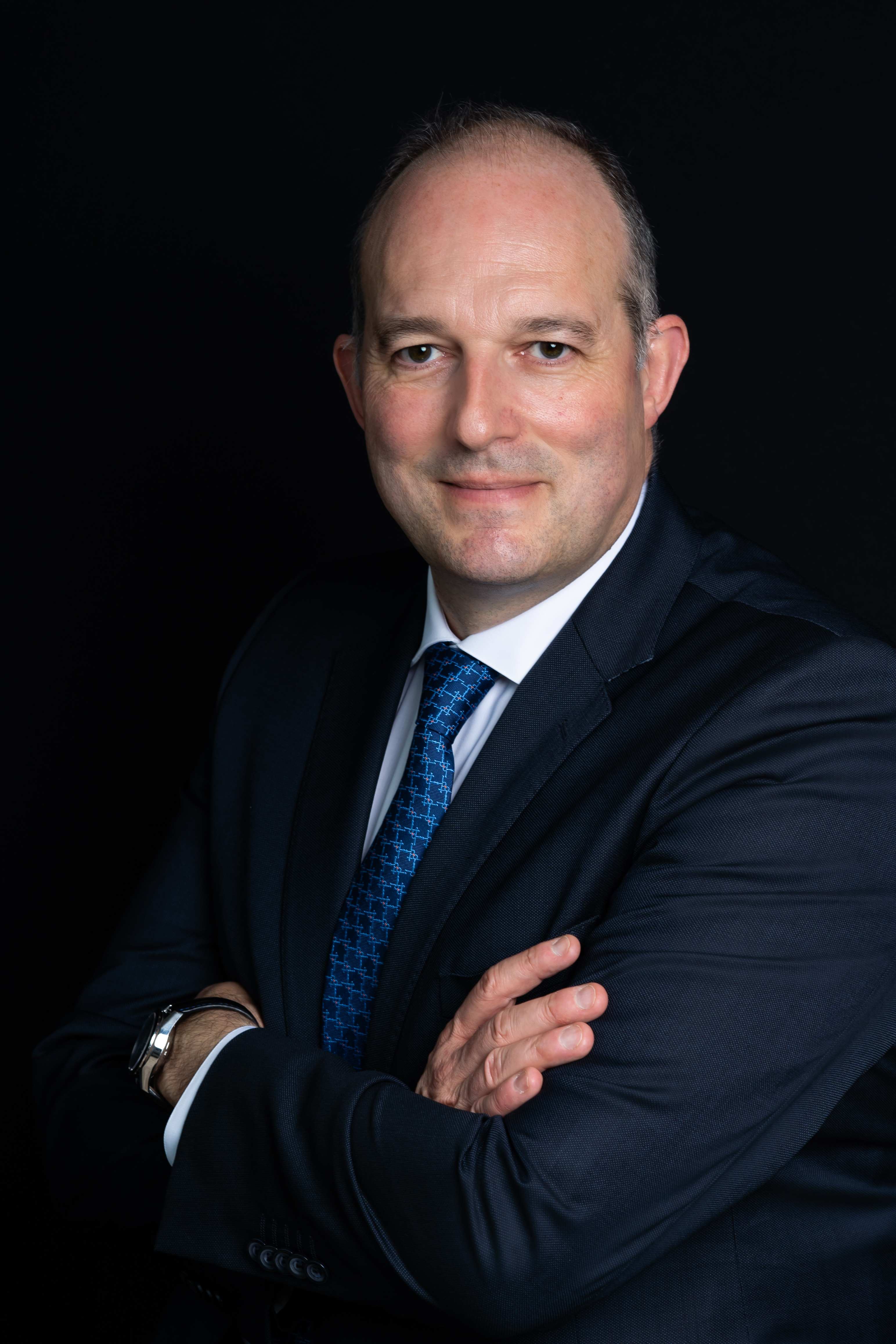 Man wearing suit and tie, smiling, dark background