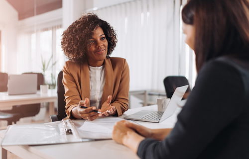 A woman consults with another person over a desk