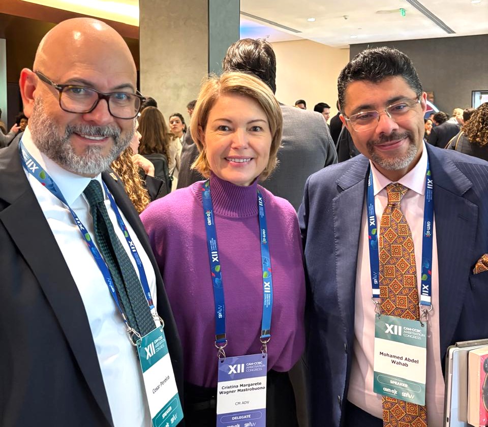 Two men and one woman smiling at the camera, at an event